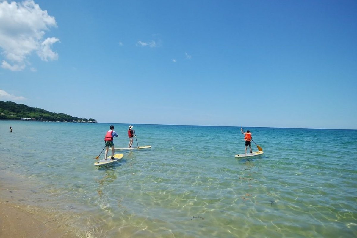 ทะเลสีฟ้าครามที่หาดโคโตกาฮามะกับผู้เล่นซัพบอร์ด