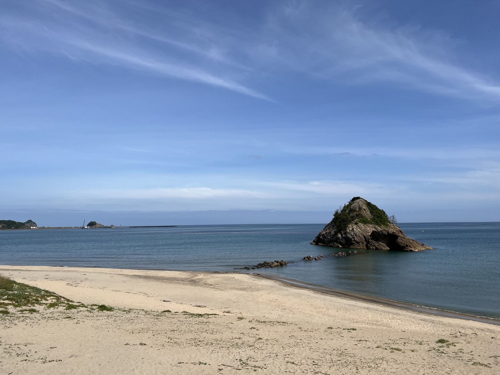 หาดทรายขาวของหาดมากิดานิที่มีเกาะหินอิบุริจิมะโผล่อยู่กลางทะเลเบื้องหน้า