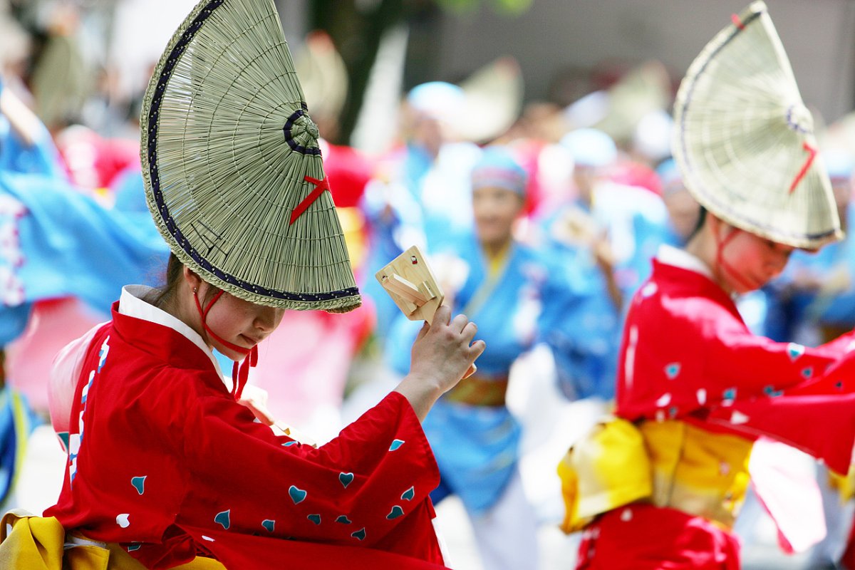นักเต้นโยซาโคอิในชุดสีสดถือเครื่องเขย่านารุโกะ
