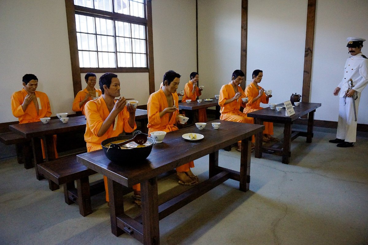 หุ่นจำลองนักโทษนั่งกินข้าวในโรงอาหารเรือนจำ