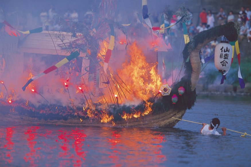 เรือไม้เล็กประดับโคมไฟลอยตามแม่น้ำคิตากามิยามค่ำ ในพิธีส่งวิญญาณวันโอบ้ง เมืองโมริโอกะ