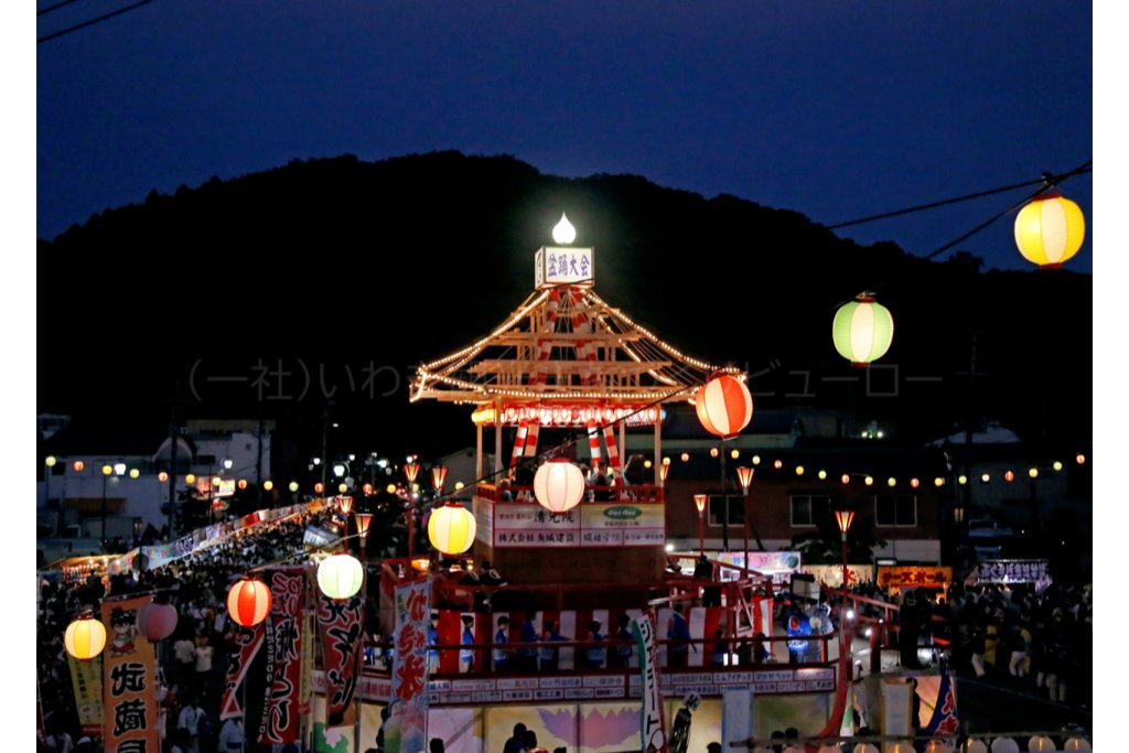 ผู้คนเต้นบงโอโดริรอบหอคอยขนาดใหญ่ที่ลานหน้าสถานีอุจิโงะ เมืองอิวากิ ยามค่ำมีโคมไฟ