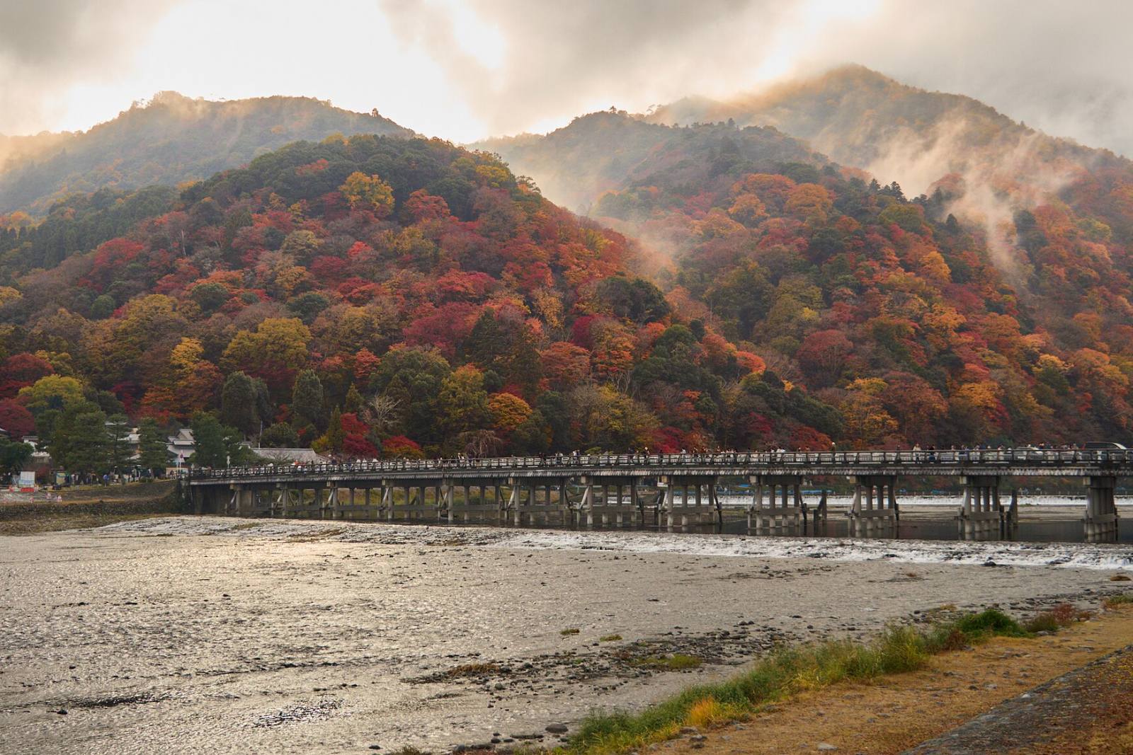 ภูเขาอาราชิยามะเปลี่ยนเป็นสีแดงและเหลืองด้านหลังสะพานโทเก็ตสึเคียว
