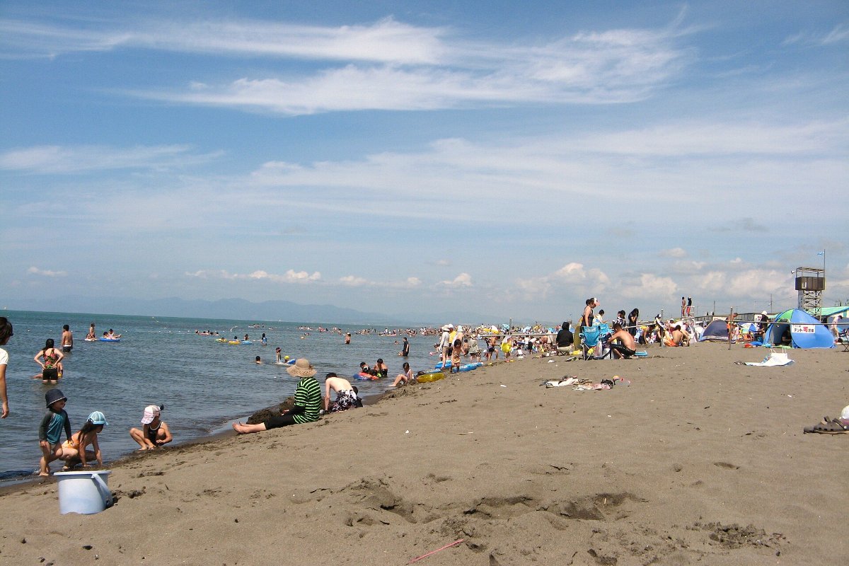 ชายหาดยาวและทะเลที่หาดอาโสบีชอิชิคาริ ฮอกไกโด มีผู้คนเล่นน้ำและบ้านริมหาดในฤดูร้อน