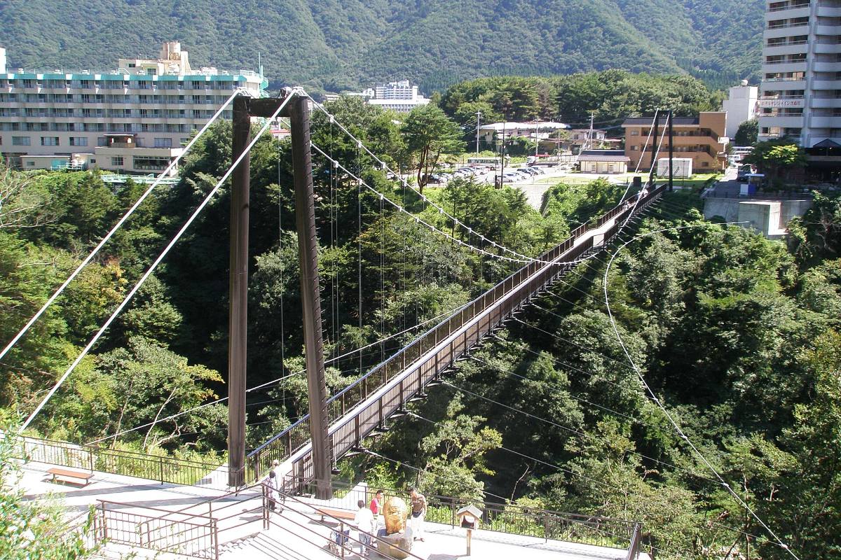 สะพานแขวนสีแดงทอดข้ามหุบเขาแม่น้ำคินุกาวะ ท่ามกลางป่าเขียว คินุกาวะออนเซ็น โทจิงิ