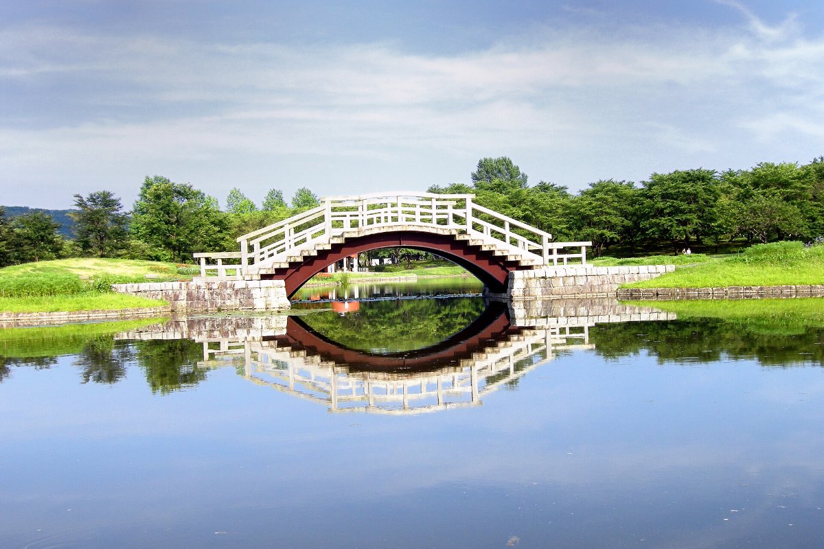 สะพานโค้งสีขาวเหนือบ่อน้ำในสวนมิจิโนกุ