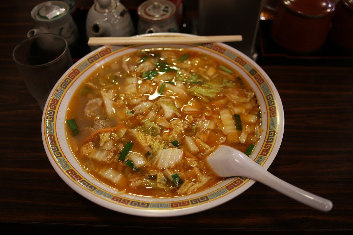 ราเม็งน้ำซุปสีแดงอมส้ม มีผักกาดขาวผัดกองสูงบนหน้า ในชามใหญ่ ราเม็งเท็นริ นารา