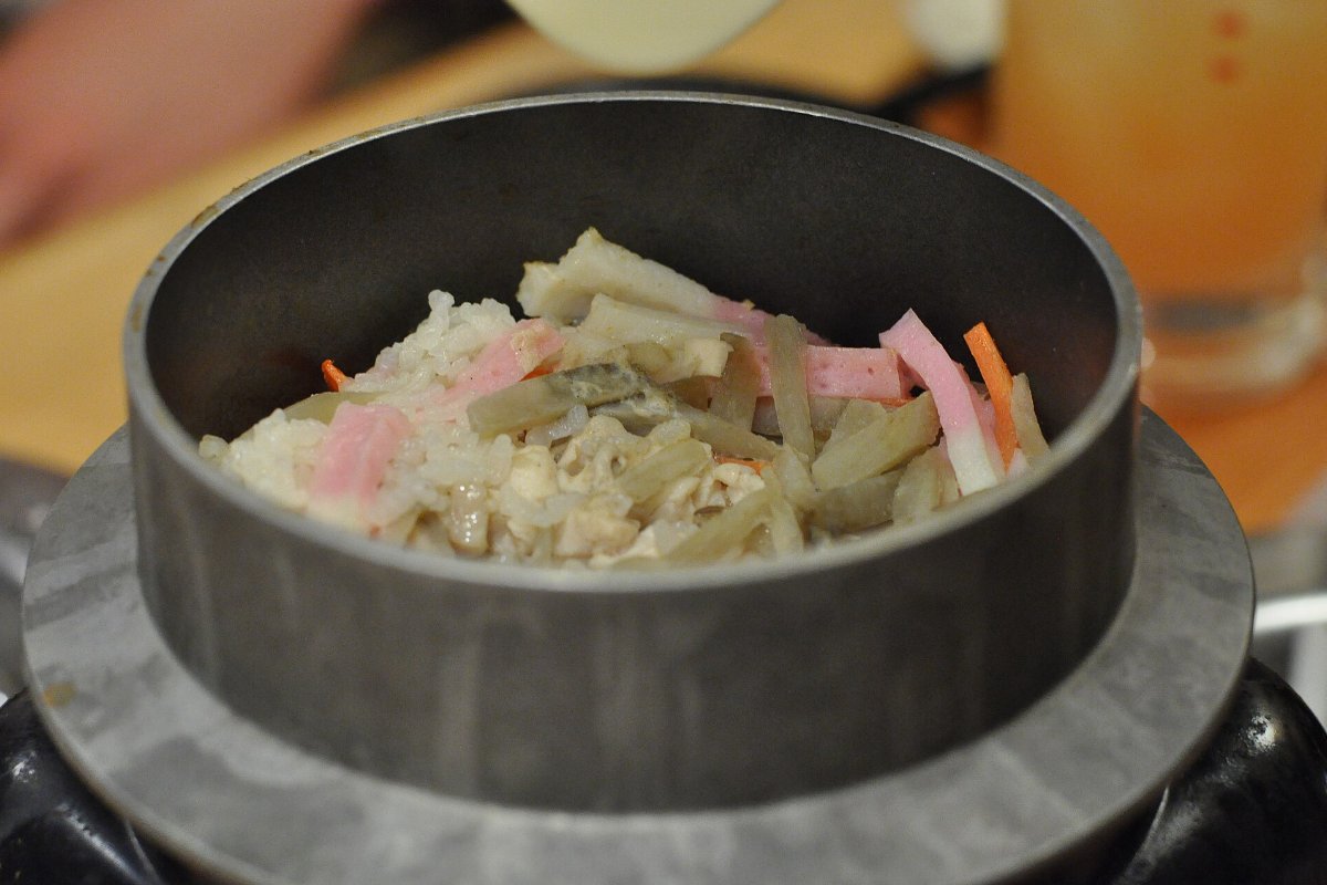 ข้าวหุงในหม้อเหล็กใบเล็ก มีผักและเนื้อหลายอย่างวางบนหน้า เปิดฝาร้อน ๆ ที่ร้านในเมืองนารา