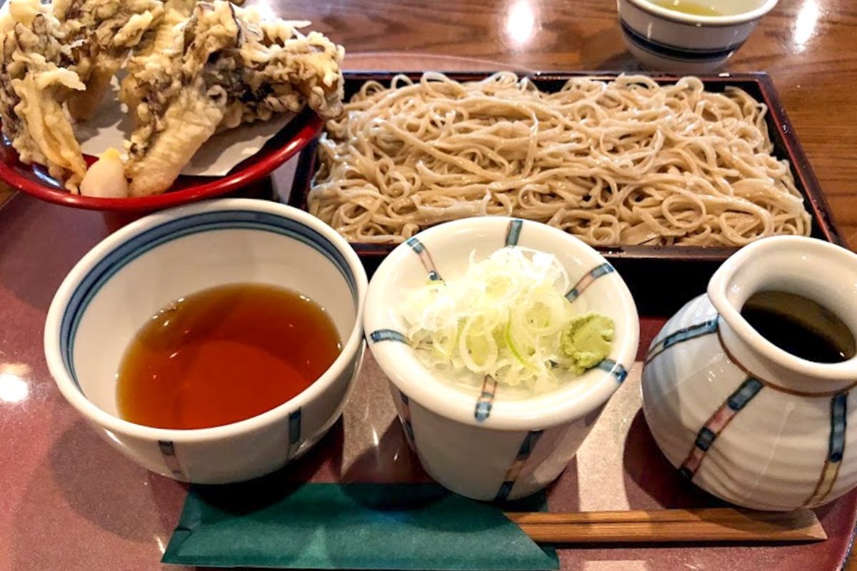 โซบะทำมือสีเทาอ่อนในกระจาดไม้ ข้างถ้วยน้ำจิ้มวอลนัต ร้านโซบะชิจิบุ