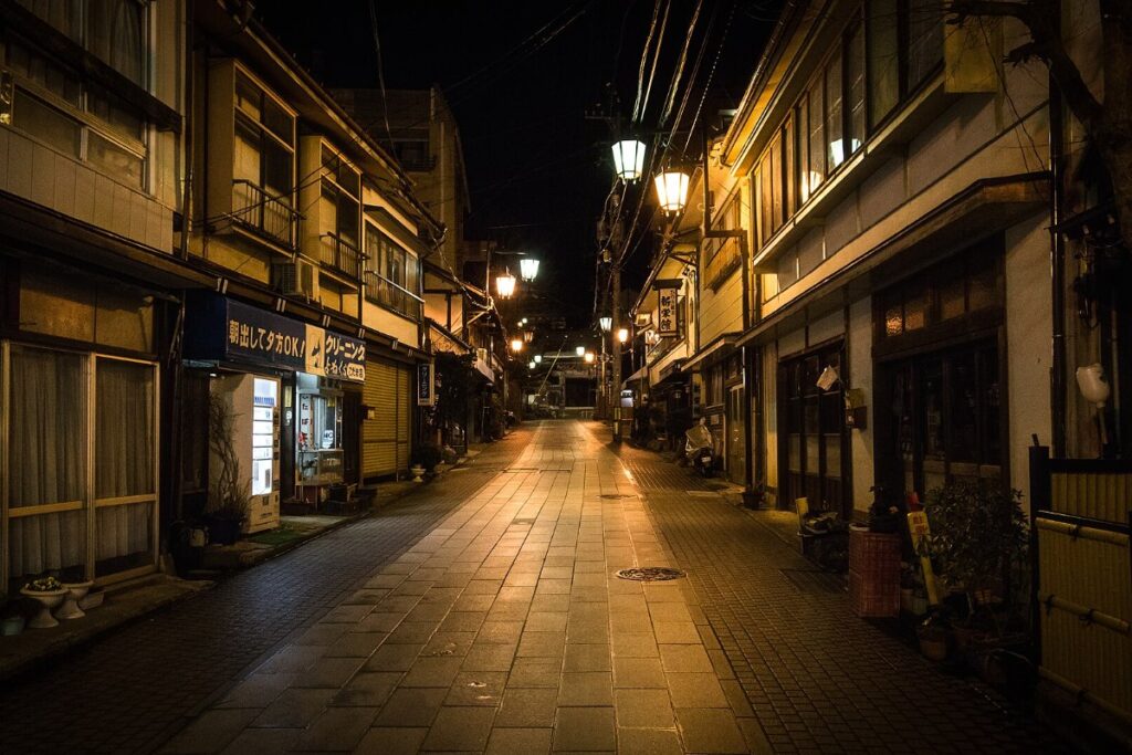 ถนนหินของชิบุออนเซ็นยามค่ำคืนในฤดูหนาว มีหิมะและแสงไฟจากโรงแรมริมถนน