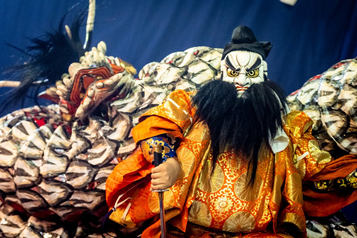 นักแสดงอิวามิคางุระในชุดหลากสีกับงูยักษ์บนเวที