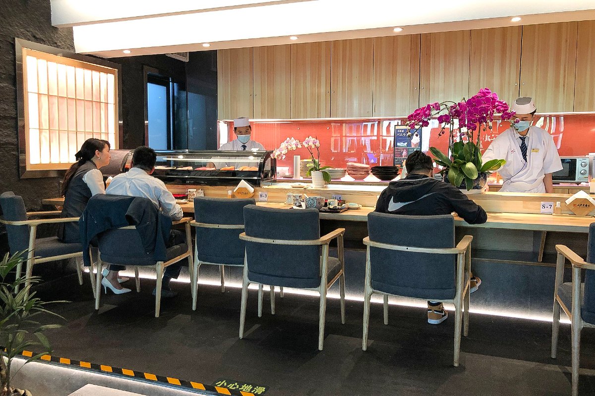 ซูชิปั้นมือหน้าปลาหลายชนิดวางเรียงบนเคาน์เตอร์ไม้ ร้านซูชิย่านสึกิจิ โตเกียว