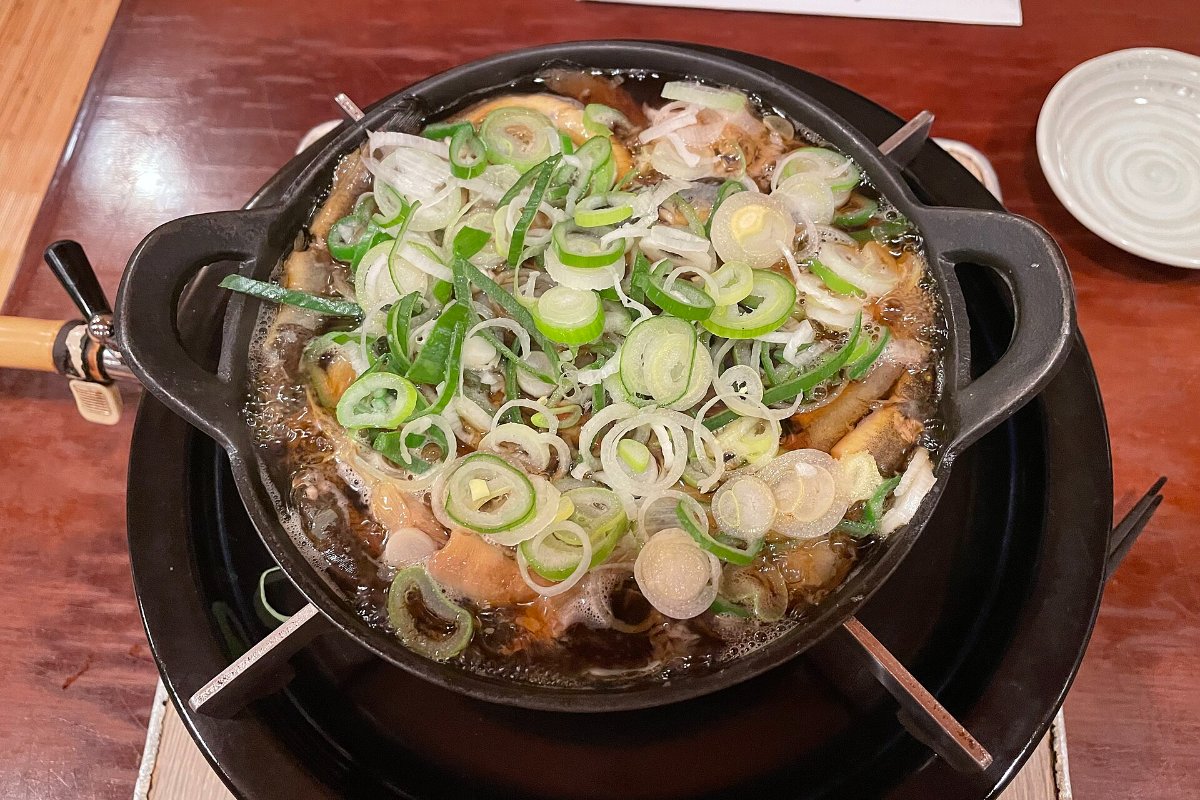 หม้อเหล็กตื้นใส่ปลาโดเซะและต้นหอมซอยวางบนเตาถ่าน ร้านเก่าย่านโคมางาตะ อาซากุสะ โตเกียว